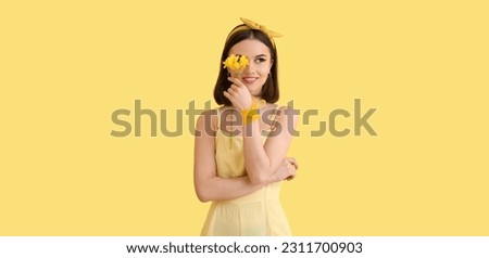 Stylish young woman with freesia flower on yellow background