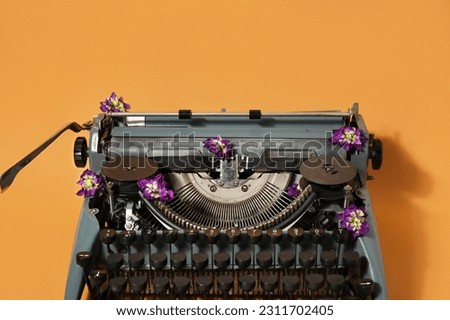 Vintage typewriter with purple flowers on orange background