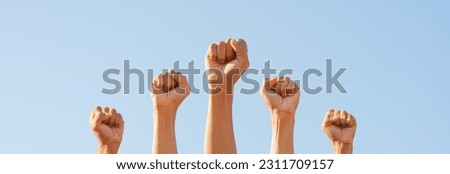 People raise fists, sky background. Power of teamwork and Competition concept Royalty-Free Stock Photo #2311709157
