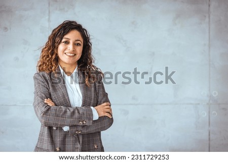 Successful businesswoman standing in creative office and looking at camera. Young latin woman entrepreneur in a coworking space smiling. Portrait of beautiful business woman 