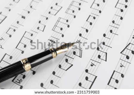 Sheet with musical notes and fountain pen, closeup view