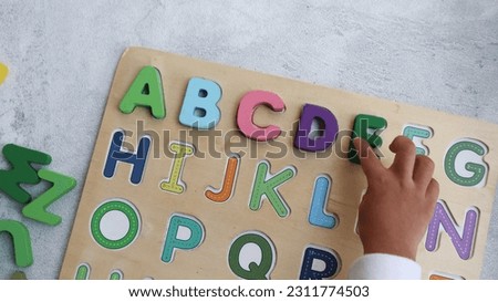 child is playing alphabet wooden puzzle