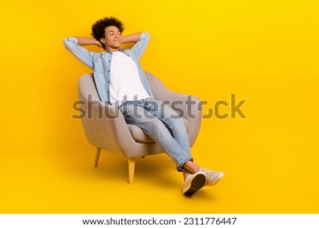 Full length photo of satisfied young person sit comfy chair closed eyes hands behind head isolated on yellow color background