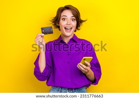Photo portrait of pretty young girl hold credit card device dressed stylish purple smart casual clothes isolated on yellow color background