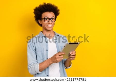 Photo of good mood man wear jeans shirt spectacles communicating modern gadget empty space isolated yellow color background