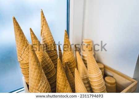 Waffle cones ready to be filled with ice cream stocked up in a wooden container. High quality photo