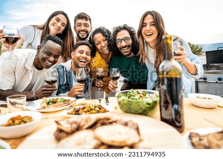 Group of young people having fun drinking red wine on balcony rooftop bbq dinner party - Happy multiracial friends eating barbecue food at restaurant terrace - Food and drink life style concept 