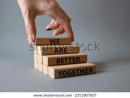 We are stronger together symbol. Wooden blocks with words We are stronger together. Businessman hand. Beautiful grey background. We are stronger together concept. Copy space.
