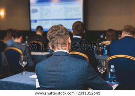 Audience at the modern conference hall listens to lecturer, people on a congress together listen to speaker on stage at master-class, corporate business seminar, venue for a congress event Royalty-Free Stock Photo #2311812641