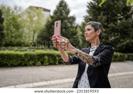 One woman mature or senior caucasian female standing outdoor alone taking selfie photos or making a video call happy smile confident real people modern lifestyle copy space