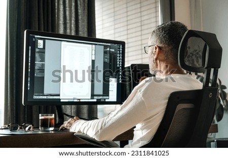 Back view of middle age man with eyeglasses working on computer at home. Royalty-Free Stock Photo #2311841025