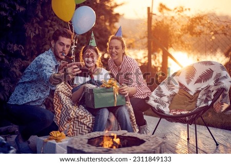 Birthday girl with cake on her face, holding a present, celebrating birthday with mom and dad. Father taking a picture. Lifestyle, celebration concept.