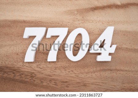 White number 7704 on a brown and light brown wooden background.
