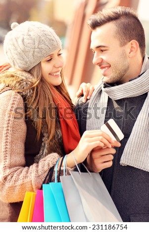 A picture of a beautiful couple shopping with a credit card in the city
