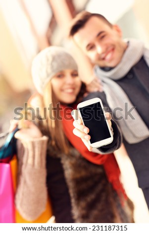 A picture of a couple showing smartphone while shopping
