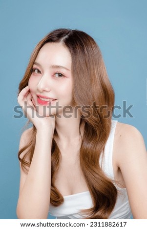 Young Asian beauty woman curly long hair with korean makeup style on face and perfect clean skin on isolated blue background. Facial treatment, Cosmetology, plastic surgery.