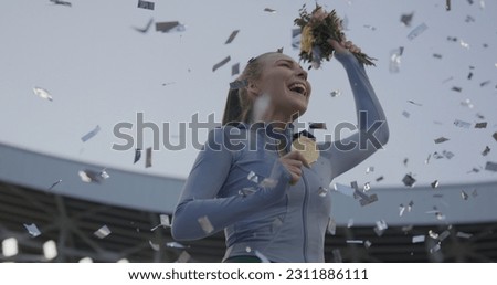 Young Female Athlete Celebrates a Win on a podium, receives a gold medal Royalty-Free Stock Photo #2311886111