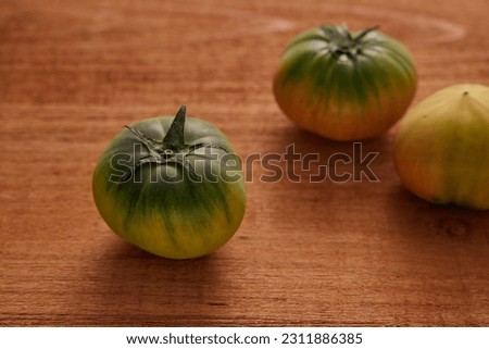3 fresh green tomatoes on a wooden table