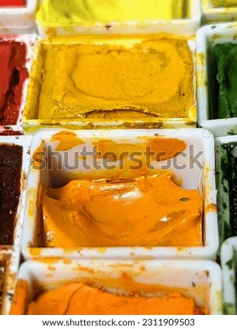 a detail of dried yellow watercolor paint from an artist paint palette.