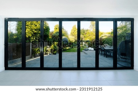 View through closed bifold doors of attractive garden in summer. Royalty-Free Stock Photo #2311912125