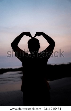  Hands making a heart shape at sunset