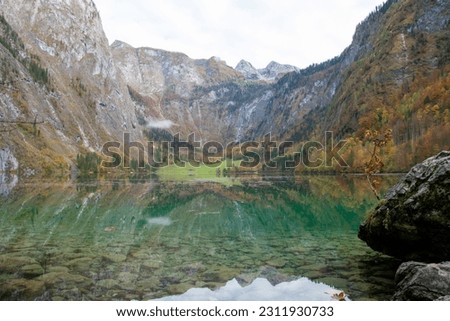 The picture shows the tranquil upper lake of the Königsee on a beautiful autumn day. The mighty mountains of the Bavarian Alps reflect beautifully in the calm water of the lake. Berchtesgaden, Germany