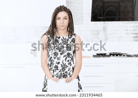 In her new kitchen, a young woman with box braids and a floral dress poses with pride. The spacious and luxurious European design enhances her quality time, be it for leisure or work from home, provid
