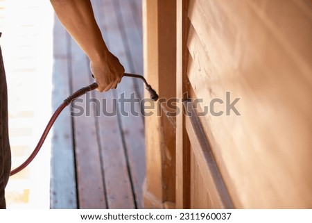 young man chooses to use termite control chemicals that are not toxic to humans mixed with water in tank for spraying to eliminate termites. enabling young man to spray termite repellant by himself Royalty-Free Stock Photo #2311960037