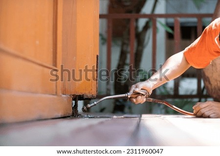 young man chooses to use termite control chemicals that are not toxic to humans mixed with water in tank for spraying to eliminate termites. enabling young man to spray termite repellant by himself Royalty-Free Stock Photo #2311960047