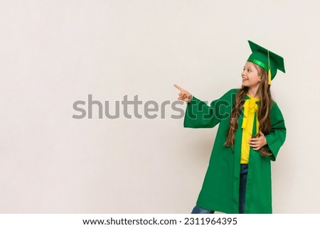A schoolgirl dressed as a master degree points to your ad. A kid at a junior high school graduation. Education for children. White isolated background. Copy space. Banner.