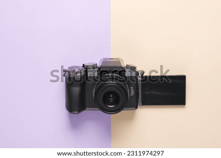 Modern digital camera with flip screen on pastel background