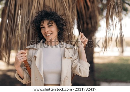 Young woman female model in beige casual outfit standing outdoors posing for portrait photo.