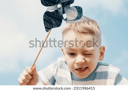 A little boy is looking down holding a pinwheel in his hand