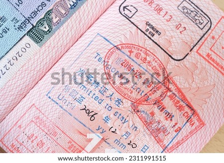close up part of pages of foreign passport with foreign visas, border stamps, china permits to enter countries, concept of traveling around the world, traveler's travel document