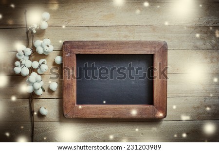 Christmas background with white winter berries and framed black board