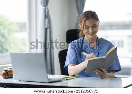 Confident female doctor, therapist sitting at desk with medical stethoscope Using a laptop and writing notes in a medical journal. planning ideas Study the treatment system, analyze life insurance.