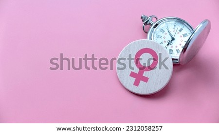 Menopause concept. Women symbol over a watch. Healthcare and medical for women. Pink background with copy space. Royalty-Free Stock Photo #2312058257