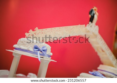 Big wedding cake. On a red background. Edible figurines Honeymoon