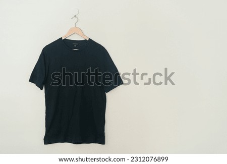 black t-shirt hanging with wood hanger on wall