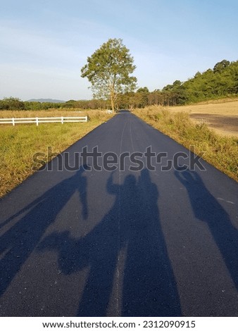 Take a picture of the silhouette of a person backlit. On a country road in the morning