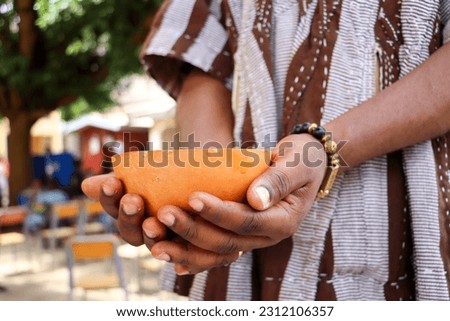 A faceless African man with a calabash in Hand ready to drink concoction or locally brewed beverage, Asaana, soobolo, saamia, ginger drink, nmedaa, coke or even fanta Royalty-Free Stock Photo #2312106357