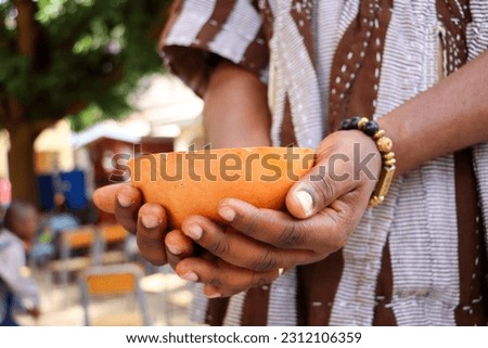 A faceless African man with a calabash in Hand ready to drink concoction or locally brewed beverage, Asaana, soobolo, saamia, ginger drink, nmedaa, coke or even fanta Royalty-Free Stock Photo #2312106359
