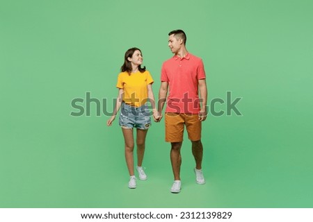 Full body happy smiling young couple two friends family man woman wear basic t-shirts together walk going hold hands look to each other isolated on pastel plain light green background studio portrait Royalty-Free Stock Photo #2312139829