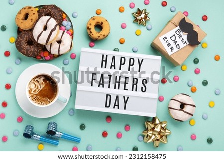 Fathers day holiday card concept with craft gift box, black moustache, cup of coffee and donuts or doughnuts on blue mint background, top view, copy space.