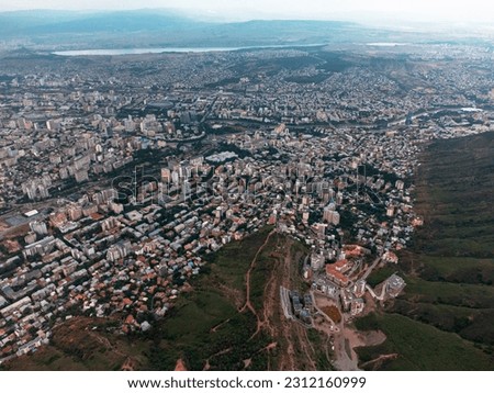 City from a bird's eye view. Photograph of the city of Tbilisi. Infrastructure, transport, streets. Panorama of the city. Hills. Cumulus clouds over the city.