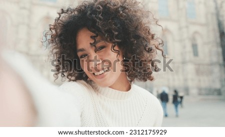 Close up, young woman is sitting down on a cell phone. Girl posing for a selfie on the old city background