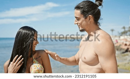 Man and woman tourist couple applying sunscreen at beach