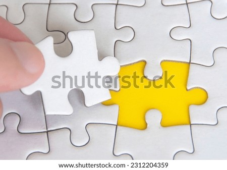 Hand holding separated jigsaw puzzle with customizable space for text. Copy space with yellow background