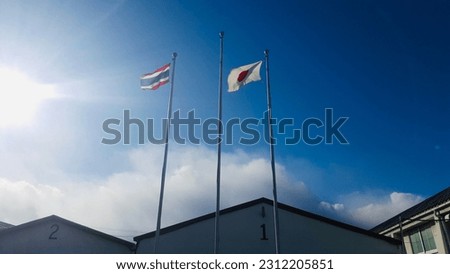 Thailand Flag and Japan Flan in a blue sky under the sun light