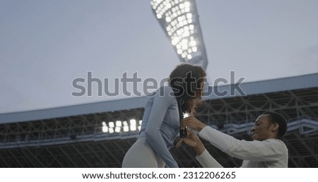 Young African-American Female Athlete Celebrates a Win on a podium, receives a gold medal Royalty-Free Stock Photo #2312206265